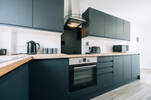 a kitchen with dark blue cabinets and a stove at Dinsdale House By Horizon Stays in Stockton-on-Tees
