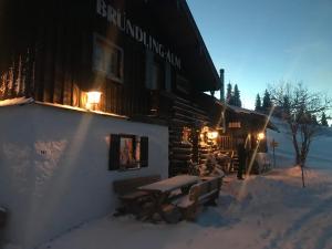 eine Blockhütte mit einem Picknicktisch im Schnee in der Unterkunft Bründling-Alm Berggasthof auf 1167m auf dem Hochfelln in Bergen