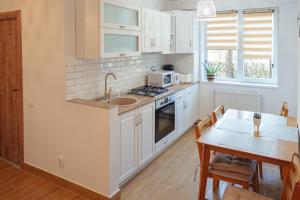 a kitchen with white cabinets and a dining table at Apart Relax Turda in Turda