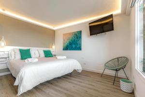 sypialnia z łóżkiem, telewizorem i krzesłem w obiekcie Pámpano Ocean View w Puerto de la Cruz