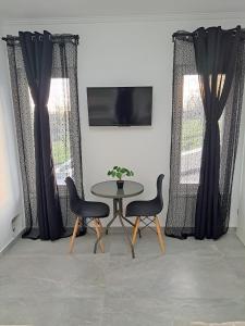 una mesa y sillas en una habitación con ventanas en Kevin&Jessica Rooms en Giarmata