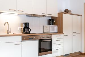 uma cozinha com armários brancos e um forno com placa de fogão em Ferienwohnung am Waldrand em Mittersill