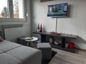 a living room with a couch and a tv on a wall at Apartman Ines in Velika Gorica