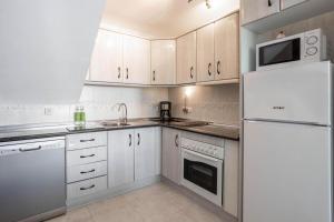 uma cozinha com armários brancos e um frigorífico branco em Shangri-La Punta Lara em Nerja
