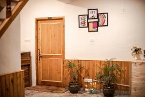 Habitación con puerta de madera y 2 macetas. en Tales N Trails, en Bashist