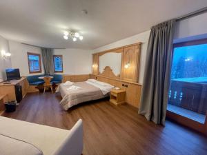 サン・マルティーノ・ディ・カストロッツァにあるHotel Villa Auroraのベッドと大きな窓が備わるホテルルームです。