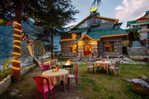 a restaurant with tables and chairs in front of a house at Tales N Trails in Vashisht