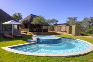 a swimming pool in a yard with an umbrella at TimBila Camp Namibia in Omaruru