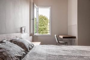 1 dormitorio con cama, ventana y escritorio en Palazzo '900 Design Flats - Il Pittore, en Padua