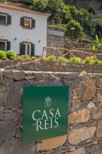 a sign on a stone wall in front of a house at Solar dos Reis by An Island Apart in Ribeira Brava