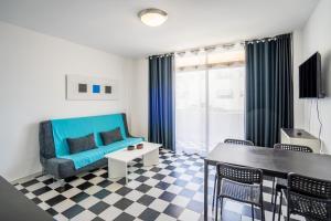 ein Wohnzimmer mit einem blauen Sofa und einem Tisch in der Unterkunft Mirada II - Formentera Break in Es Pujols