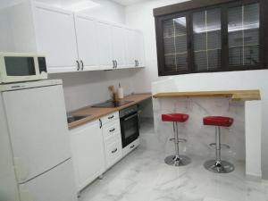 kuchnia z białymi szafkami i czerwonymi stołkami w obiekcie HELLO HOME FERIA w Madrycie
