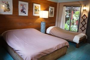 a bedroom with two beds and a lamp in it at The Riverside Guest House in Lampang