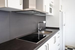 eine Küche mit Spüle und weißen Schränken in der Unterkunft Mirada II - Formentera Break in Es Pujols