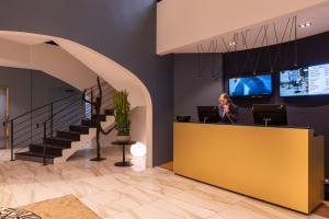 a woman standing at a reception desk in a lobby at L'Amirauté Brest in Brest