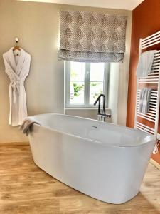 a white bath tub in a bathroom with a window at La Maison Gervaiserie & Spa in Réville