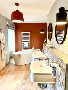La salle de bains est pourvue de 3 lavabos et d'une baignoire. dans l'établissement La Maison Gervaiserie & Spa, à Réville