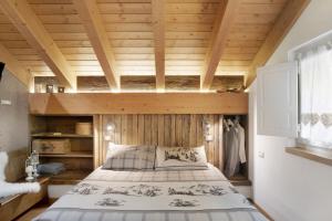 - une chambre avec un lit et un plafond en bois dans l'établissement Ca' La Vedescia Mansarda Beli Miri, à Teglio