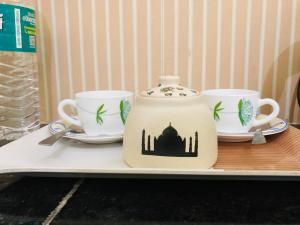 dwie filiżanki i dzbanek do herbaty na tacy w obiekcie The Lavish Stay w mieście Waranasi