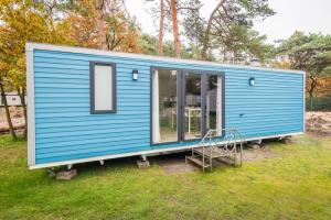 a blue tiny house sitting on top of a field at Chalet O'hara in Bilthoven