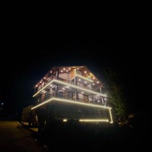 une grande maison éclairée la nuit dans l'établissement Prāṇa Boutique Stays, à Vashisht