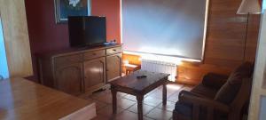 - un salon avec une télévision et une table basse dans l'établissement CASA BELLO, à San Martín de los Andes