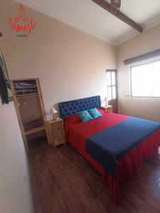 a bedroom with a bed with a blue and red blanket at Namaste Hostel in Tarija