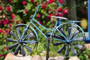 a statue of a bicycle in front of flowers at Blaues Haus in Glückstadt