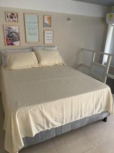 Schlafzimmer mit einem Bett mit weißer Bettwäsche und Bildern an der Wand in der Unterkunft 306Hermoso, céntrico y acogedor loft en Cartagena in Cartagena de Indias