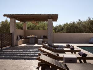 a patio with benches and a table and a pool at LaSoleil Villa, Zante Zen By ThinkVilla in Psarou