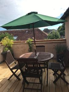 a wooden table with a green umbrella on a deck at Frog Firle View in Alfriston