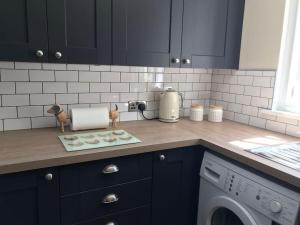 a kitchen with black cabinets and a washing machine at Frog Firle View in Alfriston