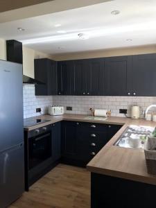 a kitchen with black cabinets and a sink at Frog Firle View in Alfriston