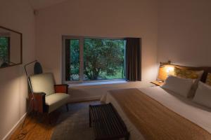 1 dormitorio con 1 cama, 1 silla y 1 ventana en Sete Cidades Lake Lodge, en Sete Cidades