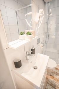 a white bathroom with a sink and a toilet at Ustronie Park - beach resort in Ustronie Morskie