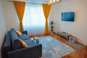 uma sala de estar com um sofá azul e uma televisão em Apart Relax Turda em Turda