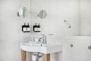 y baño blanco con lavabo y ducha. en Rederiet Hotel en Farsund