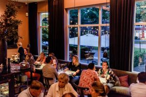 ナイメーヘンにあるBoutique Hotel Blue - Quality Lodgingsのレストランのテーブルに座っている人々のグループ