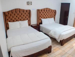 two beds in a hotel room with white sheets at Hotel Resort Thiago in Chincha Alta