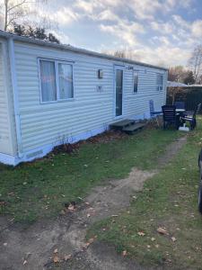 a white mobile home with a porch and two chairs at Märchencamping in Stuhr