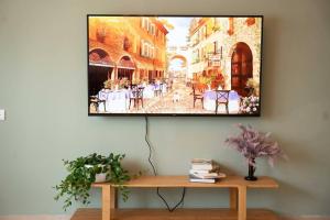 a television hanging on a wall with a picture of a street at Brand New Zippi`s- karmiel in Karmiel