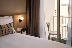 a bedroom with a bed and a chair and a balcony at Strand Suites by NEU Collective in Il-Gżira