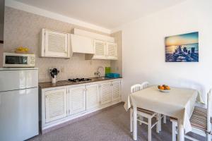 Una cocina con gabinetes blancos y una mesa con un mantel blanco. en Apartamentos Playamar - Formentera Break, en Playa de Migjorn