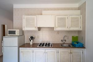 cocina con armarios blancos y nevera blanca en Apartamentos Playamar - Formentera Break en Playa Migjorn