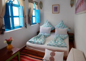 Zimmer mit einem Bett mit Kissen und einem Fenster in der Unterkunft Dar Daoud in Marrakesch