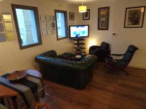 salon ze skórzaną kanapą i telewizorem w obiekcie Appartement calme en plein centre ville w mieście Granville