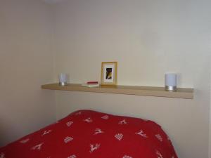 a bedroom with a red blanket and a shelf at BIENVENUE AU LIORAN in Le Lioran