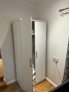 two white cabinets in a room with a mirror at Tranquil Gardens in Loughborough