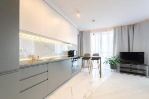 a kitchen with white cabinets and a flat screen tv at 13109 Cozy apartment nearby with Kiev Central Railway Station in Kyiv