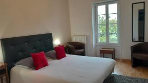 sypialnia z dużym białym łóżkiem z czerwonymi poduszkami w obiekcie Domaine de Pelouaille - chambre d'hôtes w mieście Saint-Jean-dʼAngély